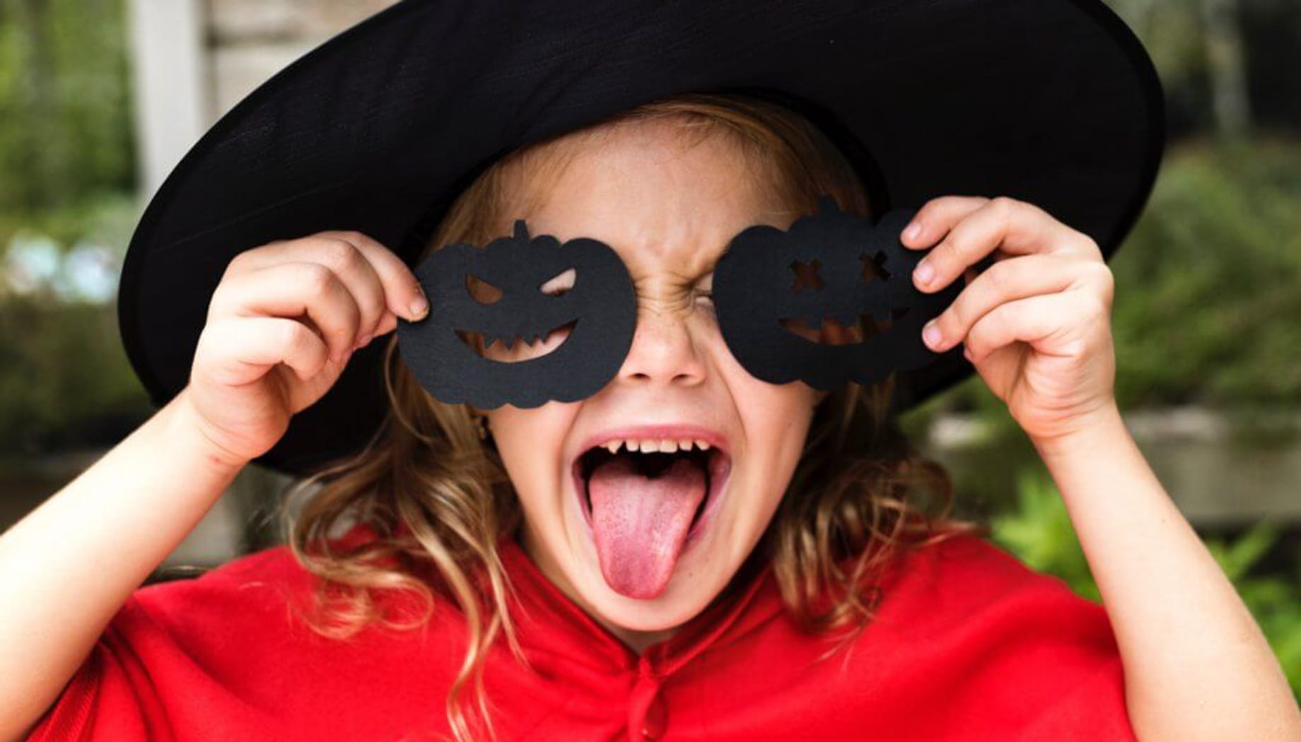 halloween Girl in a witch hat holding black Halloween pumpkin cutouts.