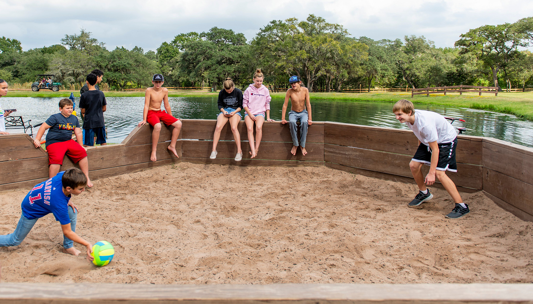 BLOG Two boys playing a game of Gaga Ball in a sand pit with people watching nearby.